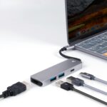Close-up view of a USB hub connected to a laptop, showcasing various ports and cables on a white surface.